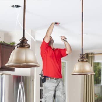 Electrician installing recessed lighting in ceiling